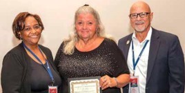 Connie Howard holding an award and smiling with two other people for a photo.