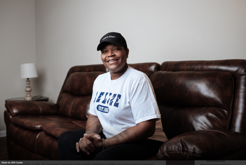 A woman in a white shirt and a black hat sitting on a brown leather couch.