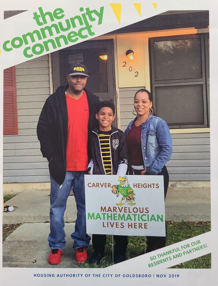 A boy posing with his parents behind a sign that says a marvelous mathematician lives here.