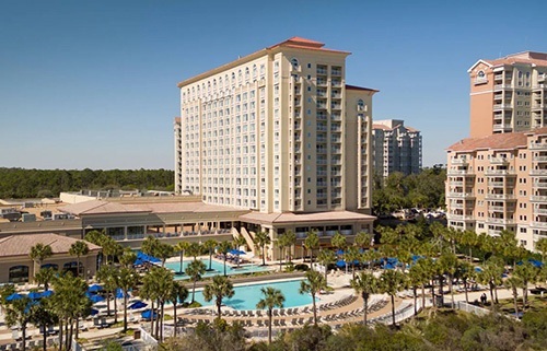 Multi-story hotel with large outdoor pool and patio seating